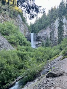 A long distance view of a waterfall surrounded by rocks and greenery.