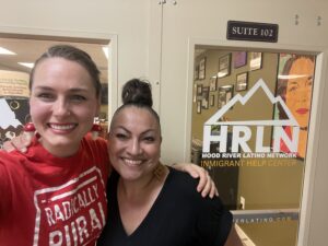 A selfie of Julianna in a red RR tshirt and Martha in front of the HRLN door sign.