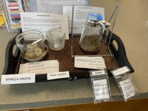 An assortment of seeds on a table with instructions and labels in English and Spanish