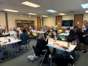 People sitting at tables with craft materials.